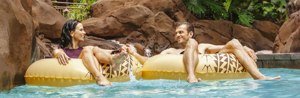 A man and a woman hold hands while floating in inner tubes