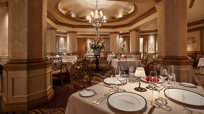 An elegant dining room with columns, a chandelier and tables at Victoria & Albert's restaurant